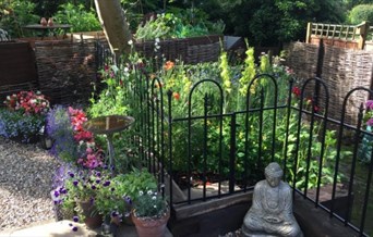 Small decorative cottage garden with pots and statues