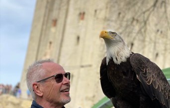 Nik Kershaw holding a bird of prey with Hedingham Castle in the background