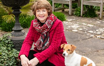 Pam Ayres sitting with her dog in a garden