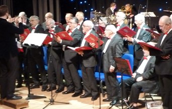 Male choirsters holding red song books
