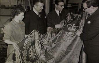 Archive photo of three men and a woman looking at Royal cloth