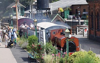 A red and black steam train with people aboad
