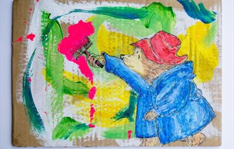 An artwork depicting Paddington Bear painting brightly coloured brush strokes on cardboard.