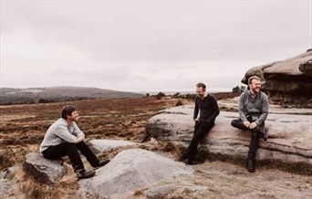 Three men sitting on rocks on moorland