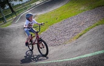 A child rides a bike on the pump track