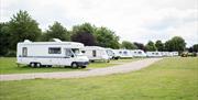 Motorhomes and caravans on touring field with gravel roadway