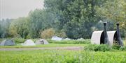 two composting toilet cabins looking over tent field with tents pitched on it