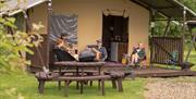 Pre-pitched safari tent with four people sat on decking in front of tent