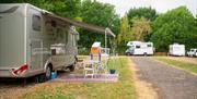 Large motorhome with awning parked on pitch with grass around it