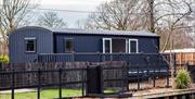 Grey shepherds hut style holiday lodge sat on riverside pitch