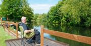 Person fishing in river from a wooden pontoon