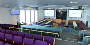 Council Chamber with screens at the front and rows of tiered seating