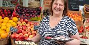 Female holding cheese samples in front of fruit and vegetable display