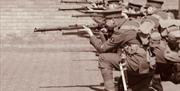 10th Essex Battalion WWI Re-enactment Group dressed as World War 1 soldiers, crouching down to fire their rifles in a line