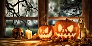 Carved pumpkins, candles and skull on windowsill