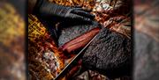 Chef cutting up large joint of barbequed meat