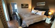 Ashdon en-suite bedroom with super-king TV bed, wooden floor and balcony with swimming pond view