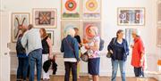 A group of people standing in front of colourful artworks in a gallery