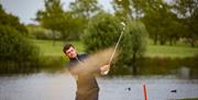 Golfer playing a shot out of a bunker at Potters Resorts Five Lakes Golf Club