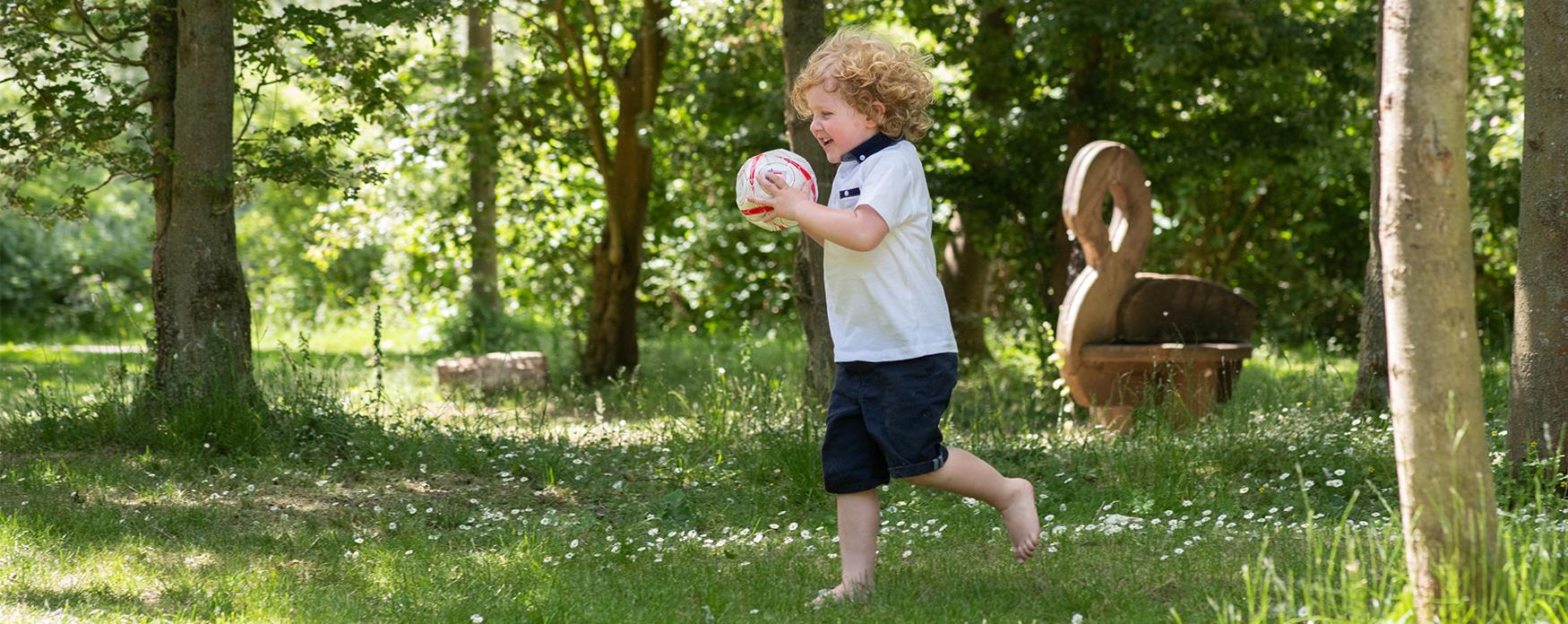 Child running with a ball in a park