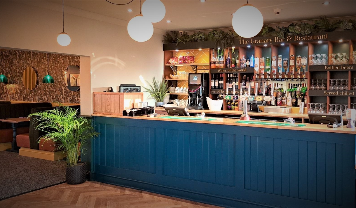 A modern bar with a blue, wooden front and a selection of drinks along the back wall