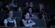 People sit smiling in our cinema watching a film playing off camera