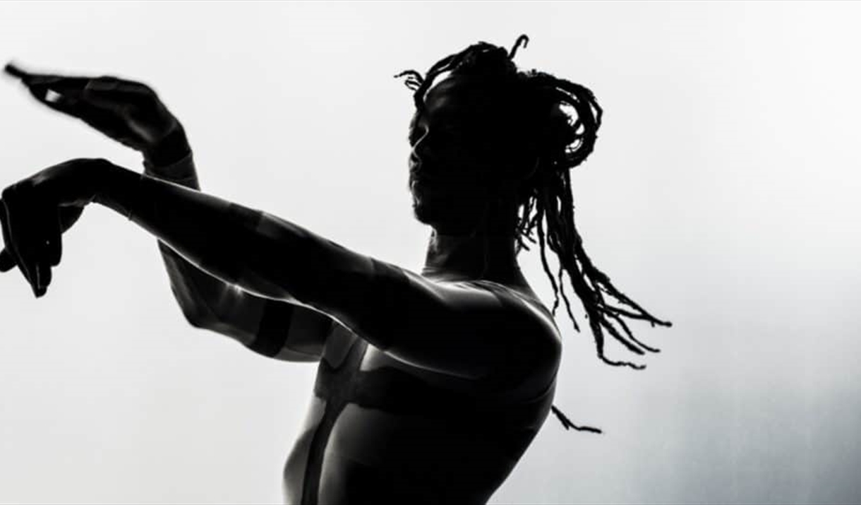 A half-silhouetted dancer gestures with his hands