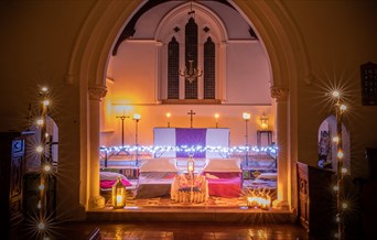Camping beds made up with lanterns and fairy lights decorating the church