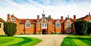 Gosfield Hall, a red brick Georgian mansion at the end of a gravel drive.