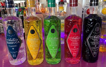 array of colourful bottles of Sambucca and other spirits