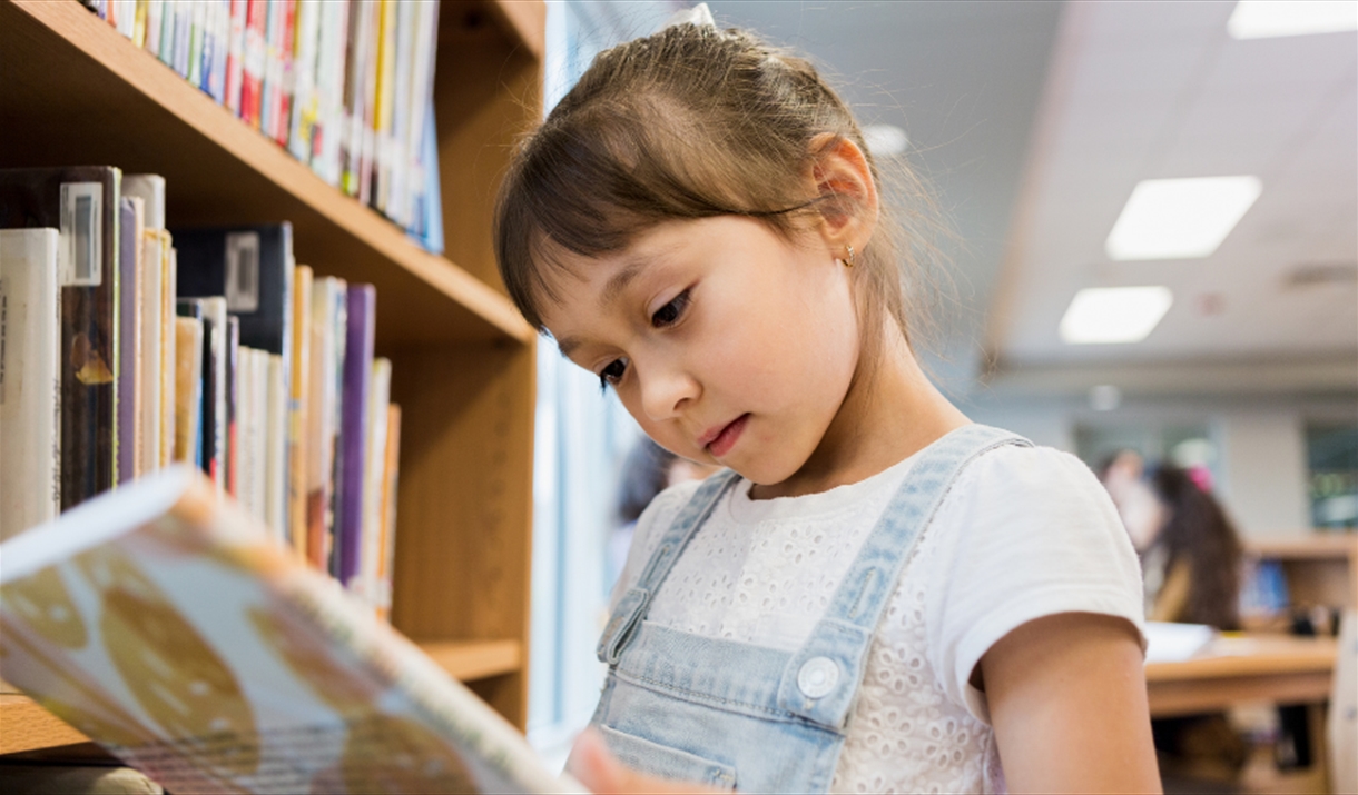 Young girl reading a library book