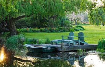 Country garden with pond, rowing boat and wooden deck chairs