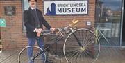 Picture shows a penny farthing bicycle and rider outside the museum.