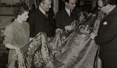 Archive photo of three men and a woman looking at Royal cloth