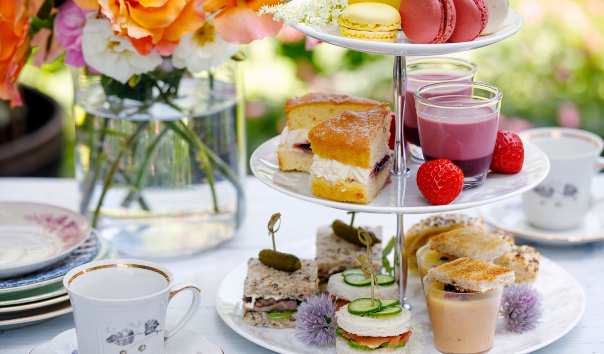 afternoon tea on traditional three-tier plate with flowers in the background