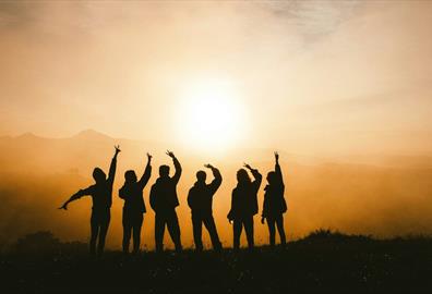 Silhouette of six people posing against a sunset