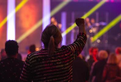 Woman watching a concert with right arm in the air
