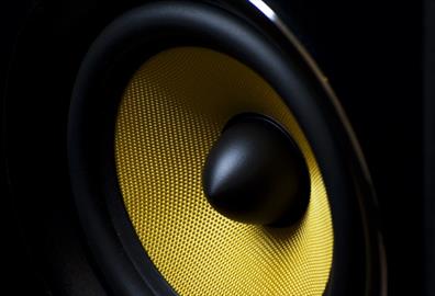 Zoomed in shot of a black speaker with bright yellow mesh