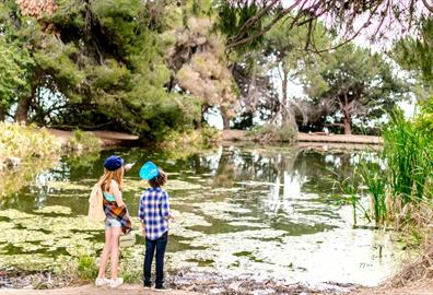 Two kids at the side of a lake in a garden