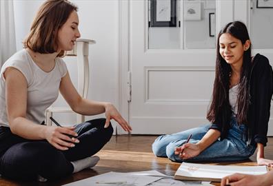 Two people sat on the floor between art supplies