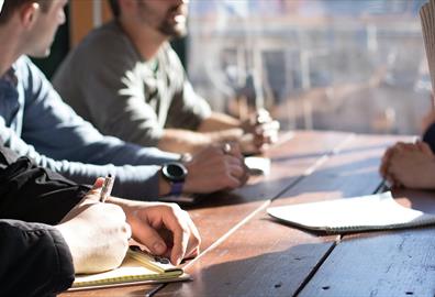 People sitting a table talking and taking notes