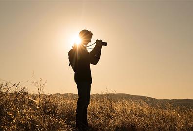 Person taking photographs in an empty field