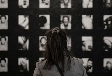 Wall of black and white photographs with person looking at them