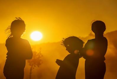 Three children silhouetted against a vibrant sunset