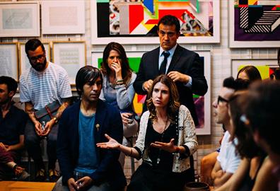 Group of people having a discussion with art on walls behind them