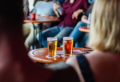 Two pints of beer on a table in a group of people