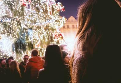 Person looking up at decorated outdoor Christmas tree