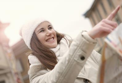 Person pointing forward in a white jacket and hat