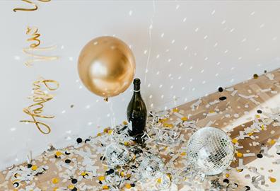 Golden confetti and disco balls with champagne bottle on the floor