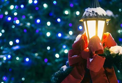 Outdoor lamp covered in snow and dressed with a red bow